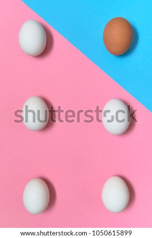 Eggs on blue and pink pastel background, copy space. Eggs on paper background with two tone color. Easter eggs. Flat lay, top view. Individuality, outstanding, uniqueness, independence