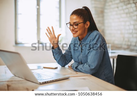 Young woman having video call via laptop in the office Royalty-Free Stock Photo #1050638456