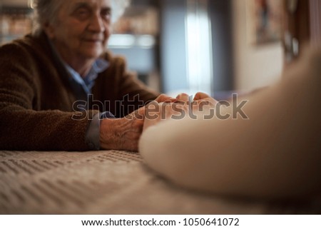Adult woman holding senior woman hands.