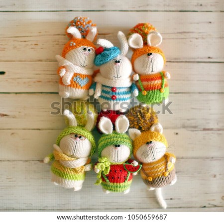 Handmade knitted toys. Easter bunnies in colorful sweaters and hats with pom-poms
