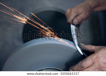 Knife sharpener and hand with blade on  table, closeup Royalty-Free Stock Photo #1050661517