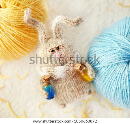 Handmade knitted toy.  Easter Bunny with bottles of lemonade among balls of yarn