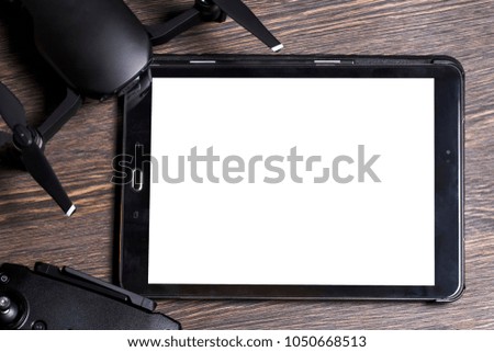 drone tablet and remote control, on a wooden background, in the middle of a white space for text
