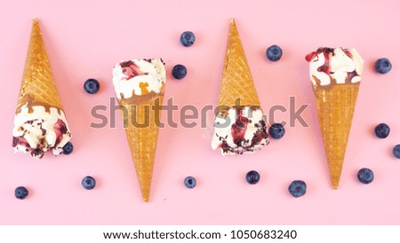 Summertime berry and chocolate Ice cream cones overhead flat lay with fresh fruit on modern pink wood table.