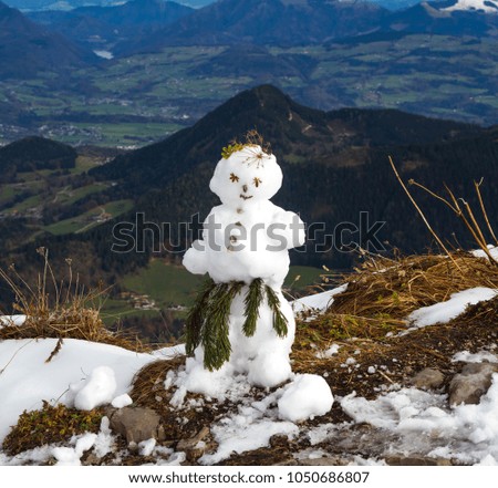A cute snowman stands on top of a mountain