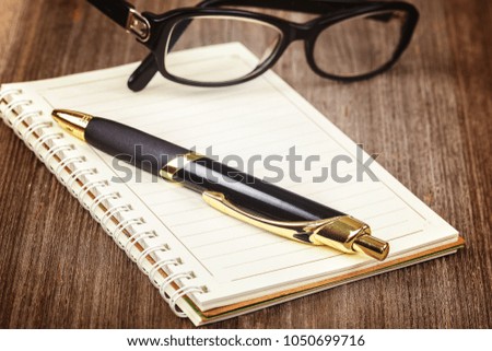 Notepad and pen on a wooden background.