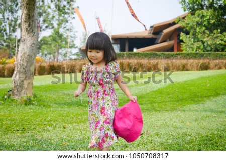 A little Asian girl walks in the yard.