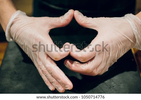 Chef hands in gloves making shape of heart, closeup