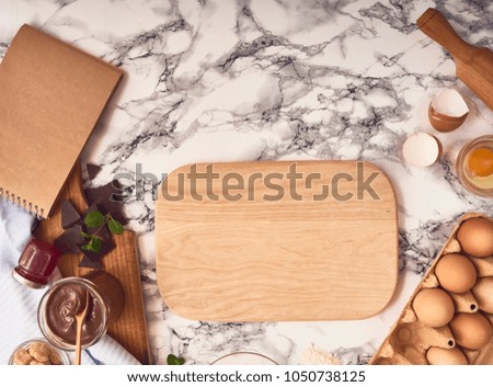 Baking or cooking background frame. Ingredients, kitchen items for baking croissants. Recipe book. Kitchen utensils, flour, eggs, chocolate, cinnamon, jam on marble texture. Text space, top view.