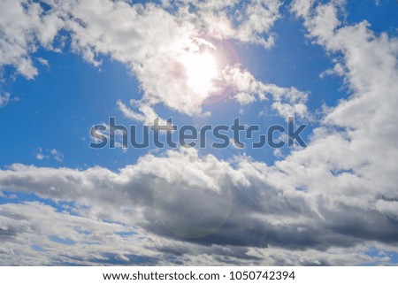 Abstract blue cloudy sky on bright day with sun flare