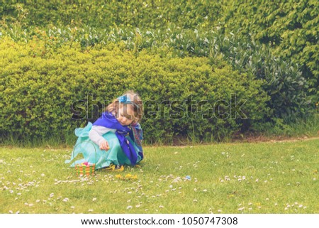 Toddler girl hunting chocolates eggs at easter, spring in gardens