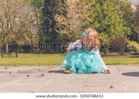 Toddler girl hunting chocolates eggs at easter, spring in terrace garden