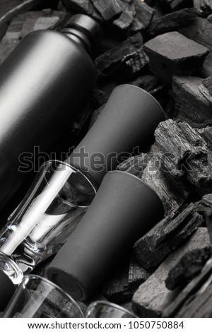 Black set of matte bottle of alcohol and shot glasses. On charcoal background. Black edition.Creative.Let's drink.Cheers.Mockup.Creative background of glass and charcoal