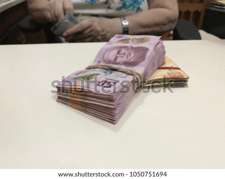 Some mexican peso money bills stacked on a beige coloured table