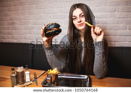 Young girl holding in female hands fast food burger, american unhealthy calories meal on background, hungry person smiling with grilled hamburger