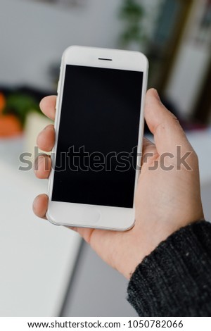 Hand hold mobile phone, person using smartphone. Top view closeup on black screen digital device mock up. Marketing technology design surface background, communication lifestyle