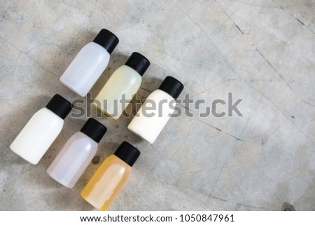 Travel-sized mini bottles cosmetic products from above on concrete table. Skincare, moisturizers, essences, body and hair treatments. Minimalism blogging concept. 