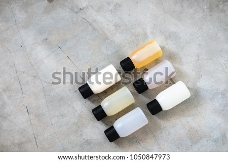 Travel-sized mini bottles cosmetic products from above on concrete table. Skincare, moisturizers, essences, body and hair treatments. Minimalism blogging concept. 