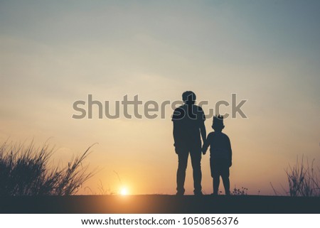 Silhouette of father and son standing together.