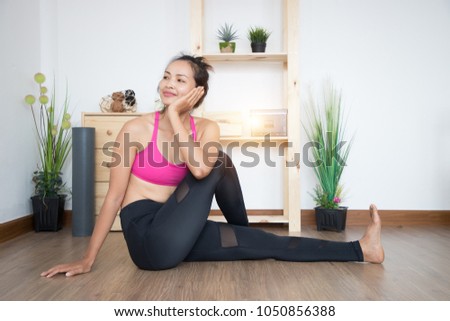Young attractive woman practicing yoga, sitting in exercise  in the house and vintage alarm clock and  bed in beautiful bedroom studio , with light near vintage alarm clock.