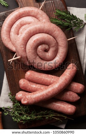 Raw sausages cooking on wooden cutting board. Top view