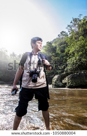 Young man traveler with a camera in the hands of a background of stunning scenery, travel, hiking, unity with nature, freedom and vacations concept