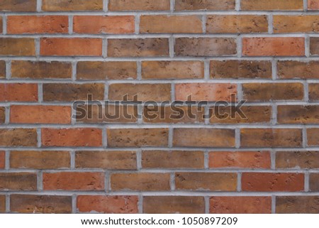 Close up view of a brick wall background comprised of red and brown earth tone color bricks in modern running bond pattern with header course bricks
