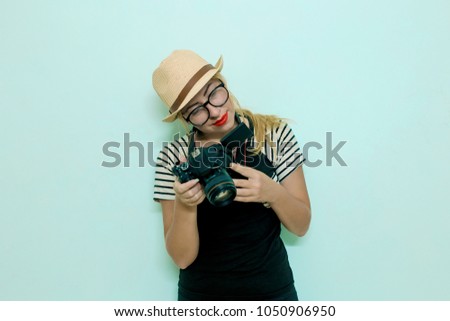 Young cheerful photographer working in studio.  Female photographer taking photos on blue background. Woman photographer takes images with dslr camera
