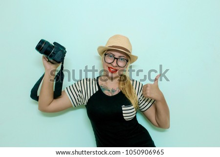 Young cheerful photographer working in studio.  Female photographer taking photos on blue background. Woman photographer takes images with dslr camera
