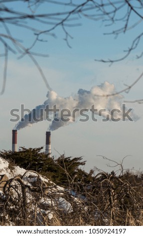 The pipe of the plant emits harmful substances into the atmosphere. Close-up on a sky background