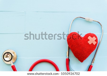 World health day, Healthcare and medical concept. Woman hand holding red heart with Stethoscope, notepad, thermometer and yellow Pill on Pastel white and blue wooden table background texture. Royalty-Free Stock Photo #1050926702