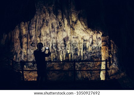 Silhouette of a man taking pictures in a cave with smartphone.