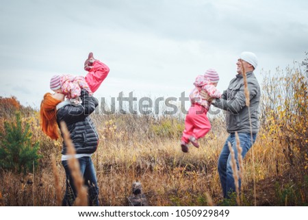 Happy family with two 1 year old girls have rest in a field full of yellow grass