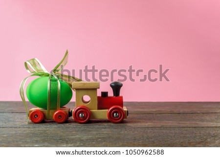 Shot of arrangement decoration Happy Easter holiday background concept.Colorful Train wood toy transfer green Easter egg gift on modern rustic brown wooden with pink paper at office desk.pastel tone.