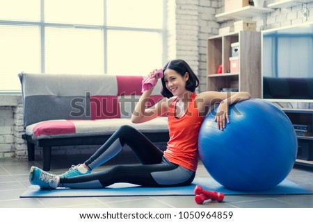 Asian woman wiping her sweat after a workout at home. Royalty-Free Stock Photo #1050964859