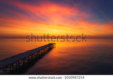 Aerial view over the old broken bridge in the sea, sunrise shot