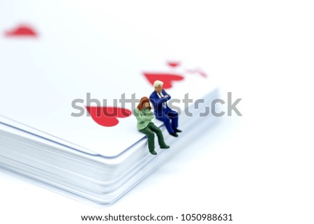 Miniature people : sitting on playing card.