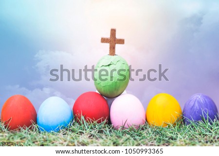wooden cross in cracked  green egg and colorful  on green grass over blur cloudy sky background, Easter background,copy space