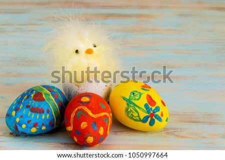 Conceptual image of Easter with baby chicken next to eggs on blue wooden background with copyspace