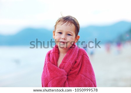 Little boy kid is warming up with towel on the beach
