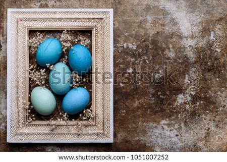 Happy Easter rustic background with copy space. DIY dyed various shades of blue Easter eggs and vintage wooden picture frame mock up.
