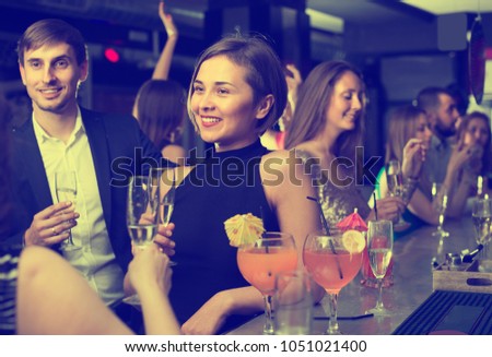 Young female is drinking cocktails with colleague at corporate event in bar. 
