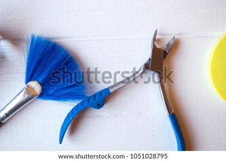 Blue brush and nail scissorson a white wooden desk.
