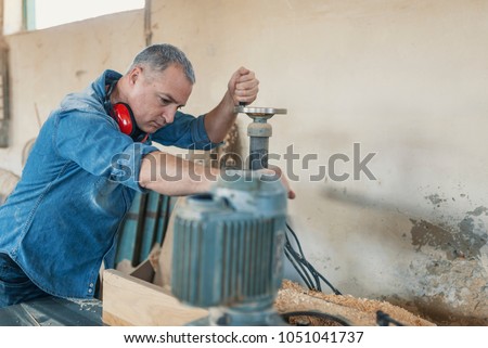 Carpenter using electric saw in carpentry. profession, carpentry, woodwork and people concept. Carpenter working on woodworking machines in carpentry shop.