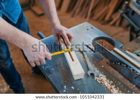 Carpentry workshop. Carpenter with ruler measuring wood plank at workshop. Craftsman holding ruler on wooden planknear other tools. Close up of unrecognizable carpenter marking measurements 