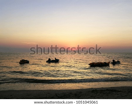 Sunset on the beach with banana boat and jet ski.