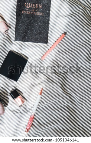 Woman's glamour beauty products flatlay on white and gray striped bedsheets. Fashion blogging concept