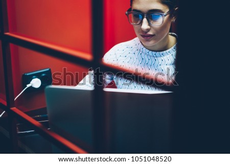 Concentrated businesswoman sitting in skype booth during teleconference on netbook,serious female watching online webinar during online courses via laptop computer in skype cabin with noise insulation Royalty-Free Stock Photo #1051048520