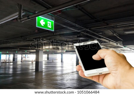 Man use mobile phone, blur image of parking in the building.