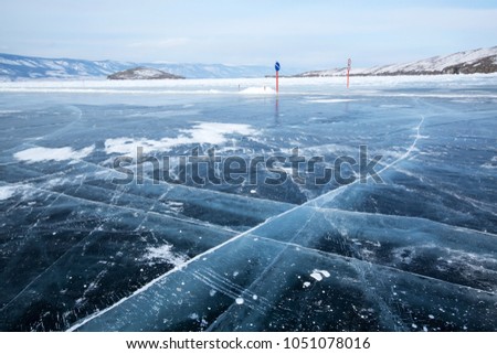 Lake Baikal in winter day. Cracks on the smooth surface of the ice near the cliffs of Olkhon Island.
